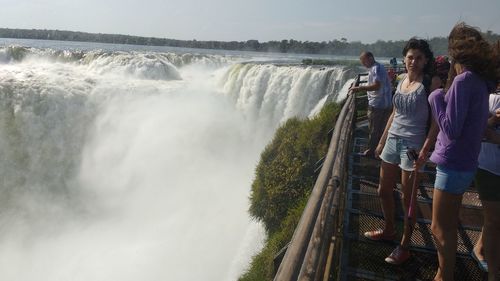 Rear view of people looking at waterfall