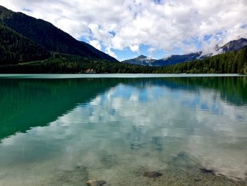 Scenic view of lake and mountains against cloudy sky
