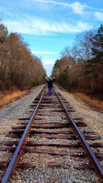 Rear view of person walking on railroad track