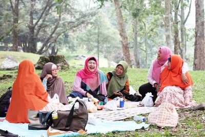 Smiling friends wearing hijab while enjoying in picnic