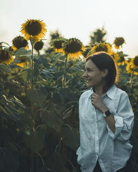 Young woman standing against plants