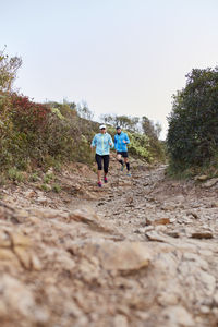 Couple running on dirt road in path at morning