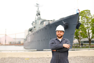 Sailor standing against ship at harbor