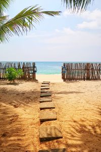 Boardwalk leading towards sea at beach against sky