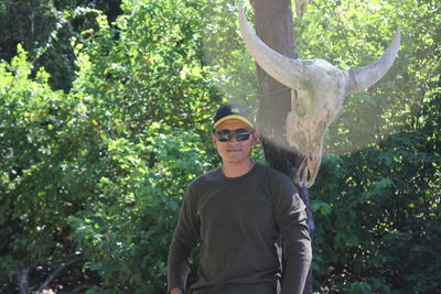Portrait of man wearing sunglasses standing against plants