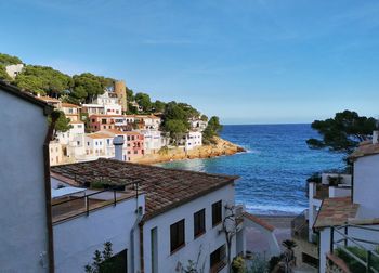 Buildings by sea against blue sky