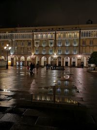 Reflection of building on wet street at night