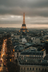 Illuminated buildings in city against cloudy sky