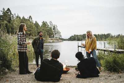 People sitting by lake against sky