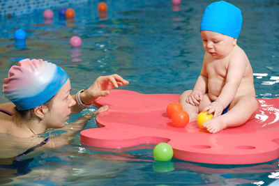 Early age swimming in pool. baby boy trained to swim in water. happy child with trainer woman in