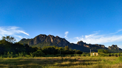 Scenic view of landscape and mountains against blue sky