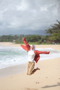 Full length of woman jumping on beach