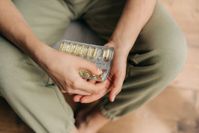 Close-up woman holding pack of omega 3 fish oil capsules