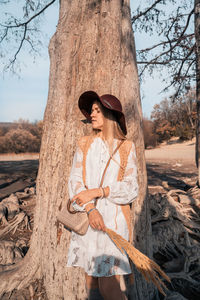 Woman standing by tree trunk