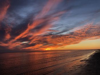 Scenic view of sea against dramatic sky during sunset