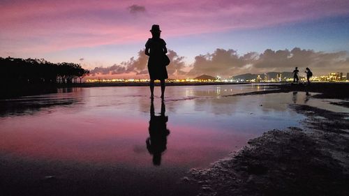 Silhouette man standing on beach against sky during sunset