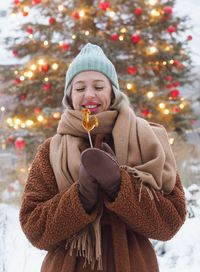 Young beautiful stylish blonde woman with lollipop in winter park