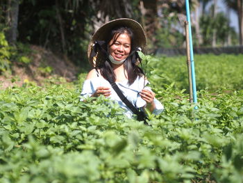 Portrait of young woman standing amidst plants