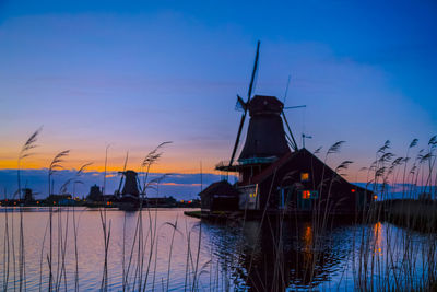 Sunset landscape with windmills and field wild herbs and flowers. silhouettes of dutch mills 