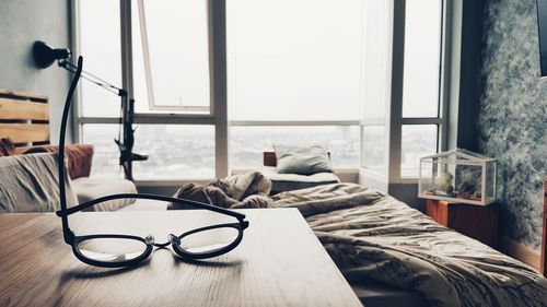 Close-up of eyeglasses on table by bed
