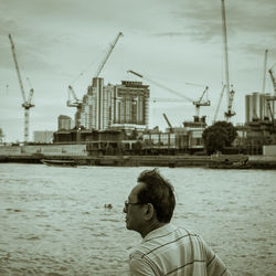 Cranes at harbor against sky