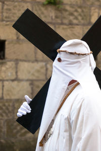 Person wearing traditional clothing while carrying cross