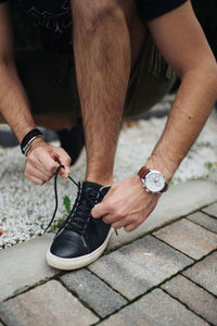 Urban young guy tying his shoe on getting ready to go