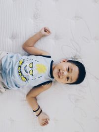 Directly above view of happy boy lying on bed