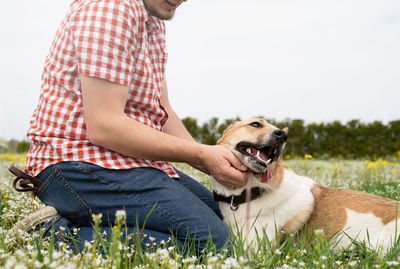 Side view of man with dog sitting on grass