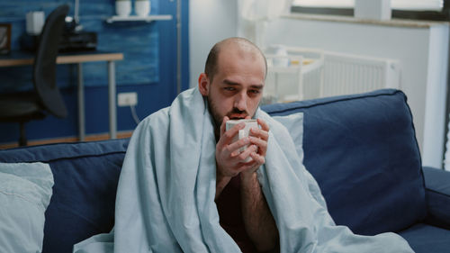 Portrait of man sitting on bed