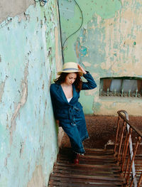 Portrait of young woman standing against wall