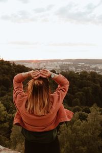 Rear view of woman standing against sky during sunset