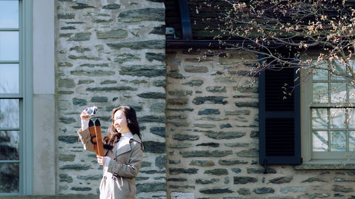 Young woman standing against building