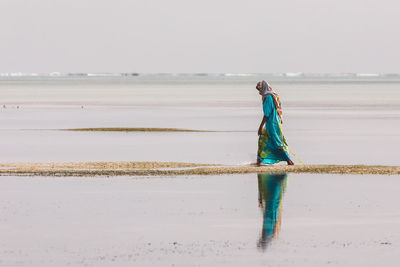 Rear view of woman standing on beach