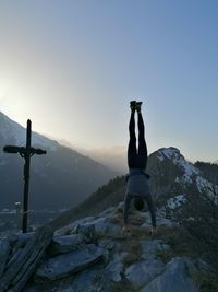 Man standing on rock against sky