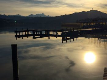 Silhouette wooden posts in lake against sky during sunset