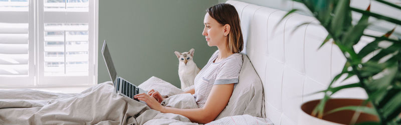 Side view of young woman sitting on bed