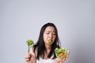 Portrait of woman holding ice cream against white background