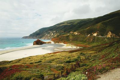 Scenic view of sea by mountains against sky