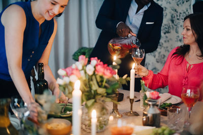 Midsection of man pouring drink to friend at dining table in party