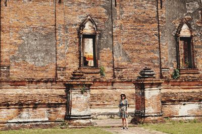 Woman standing against old building