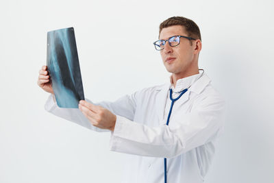 Portrait of doctor using mobile phone against white background