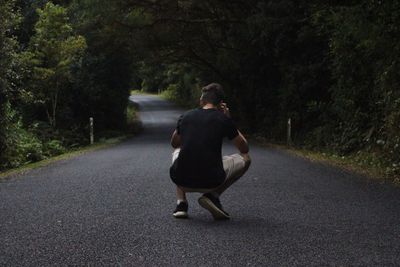 Rear view of woman walking on road amidst trees