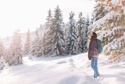 Rear view of woman walking on snow covered field