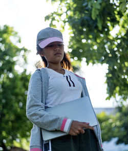 Portrait of young woman reading book while standing outdoors