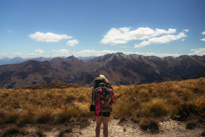 Rear view of man standing on mountain against sky