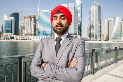 Portrait of businessman wearing turban standing against river