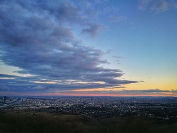 Aerial view of illuminated city against sky at sunset