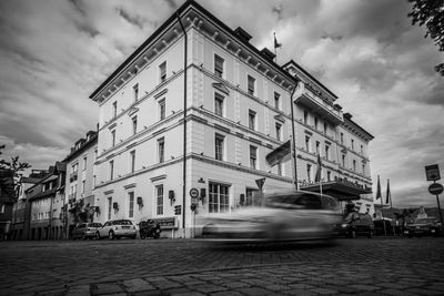 Cars on street by buildings in city against sky