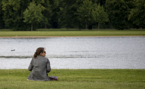 Side view of woman looking at lake against trees